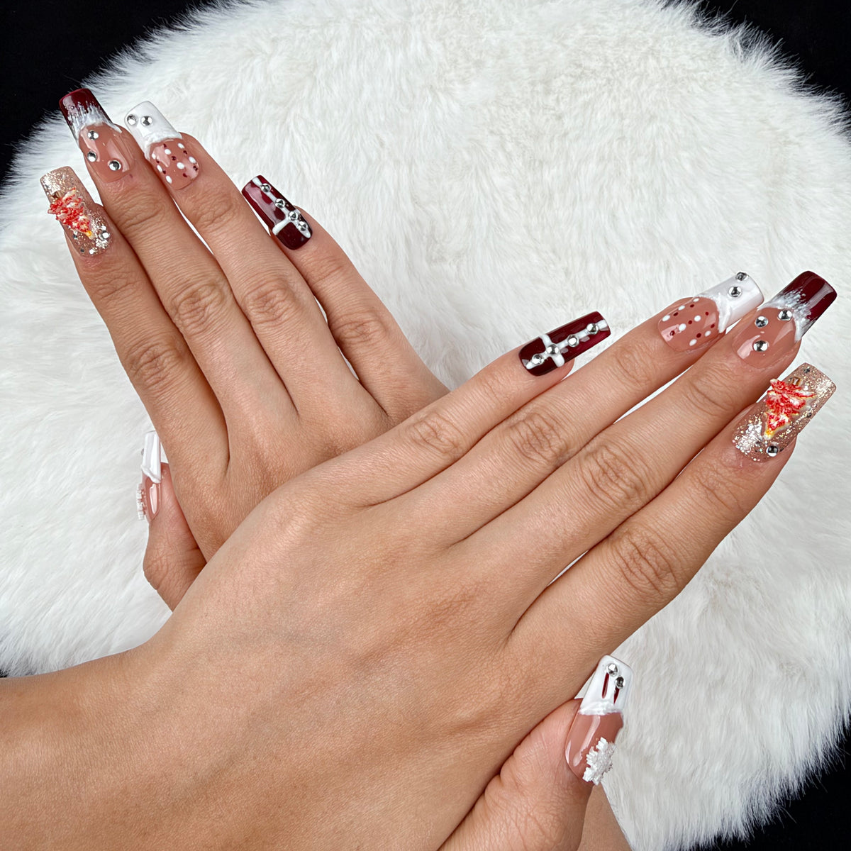 Close-up of hands wearing Winter Rose burgundy glitter and white snowflake Christmas square press-on nails