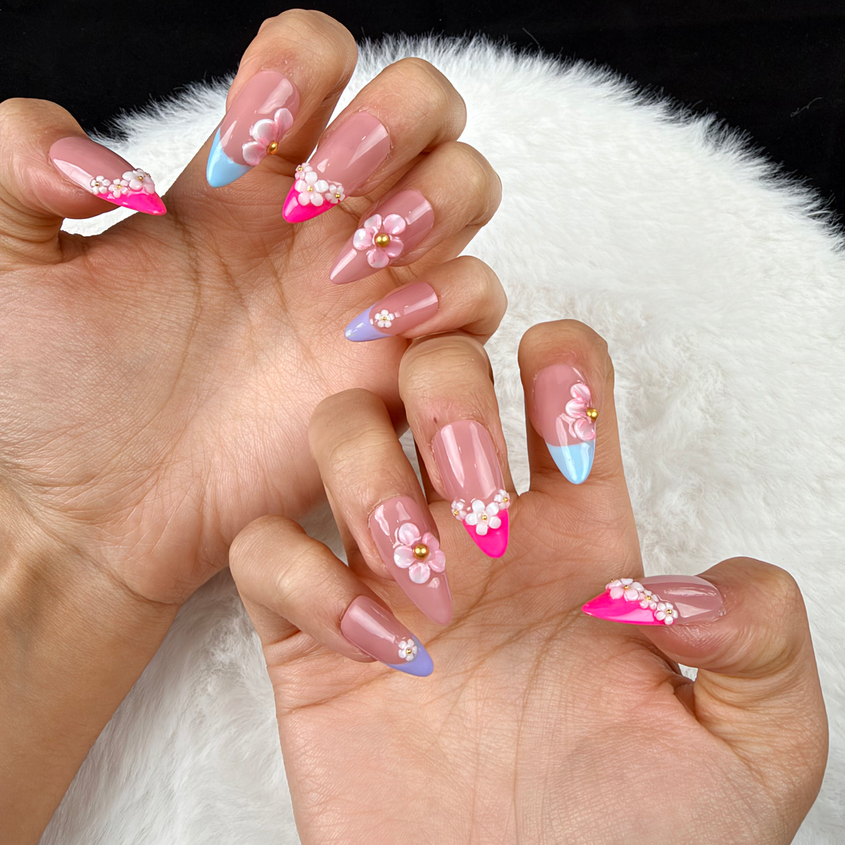 Close-up of hands wearing Floral Canopy pink, blue and lilac French tip floral almond press-on nails