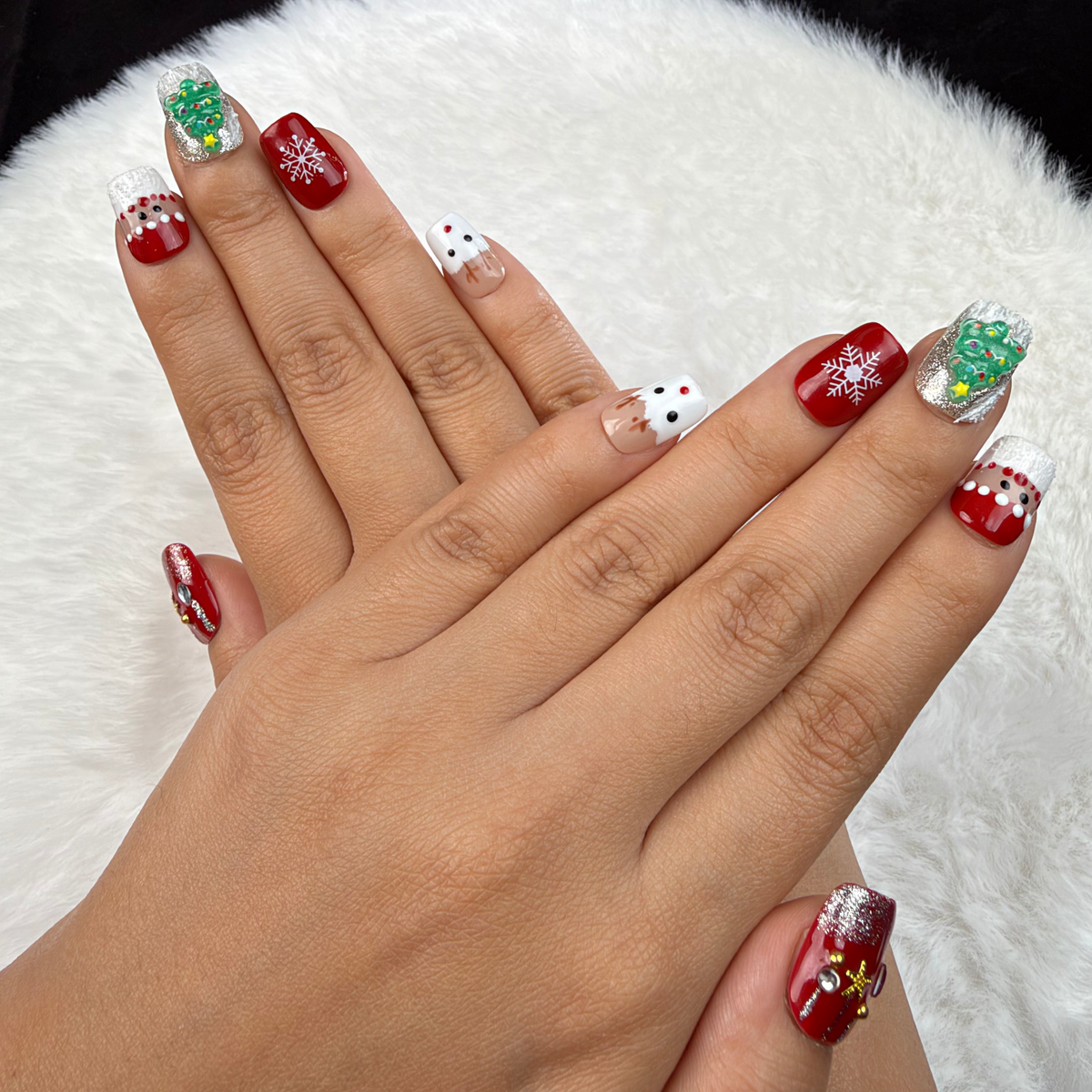 Detail shot of Christmas Patchwork red and green Christmas square press-on nails with trees and snowflakes on hand