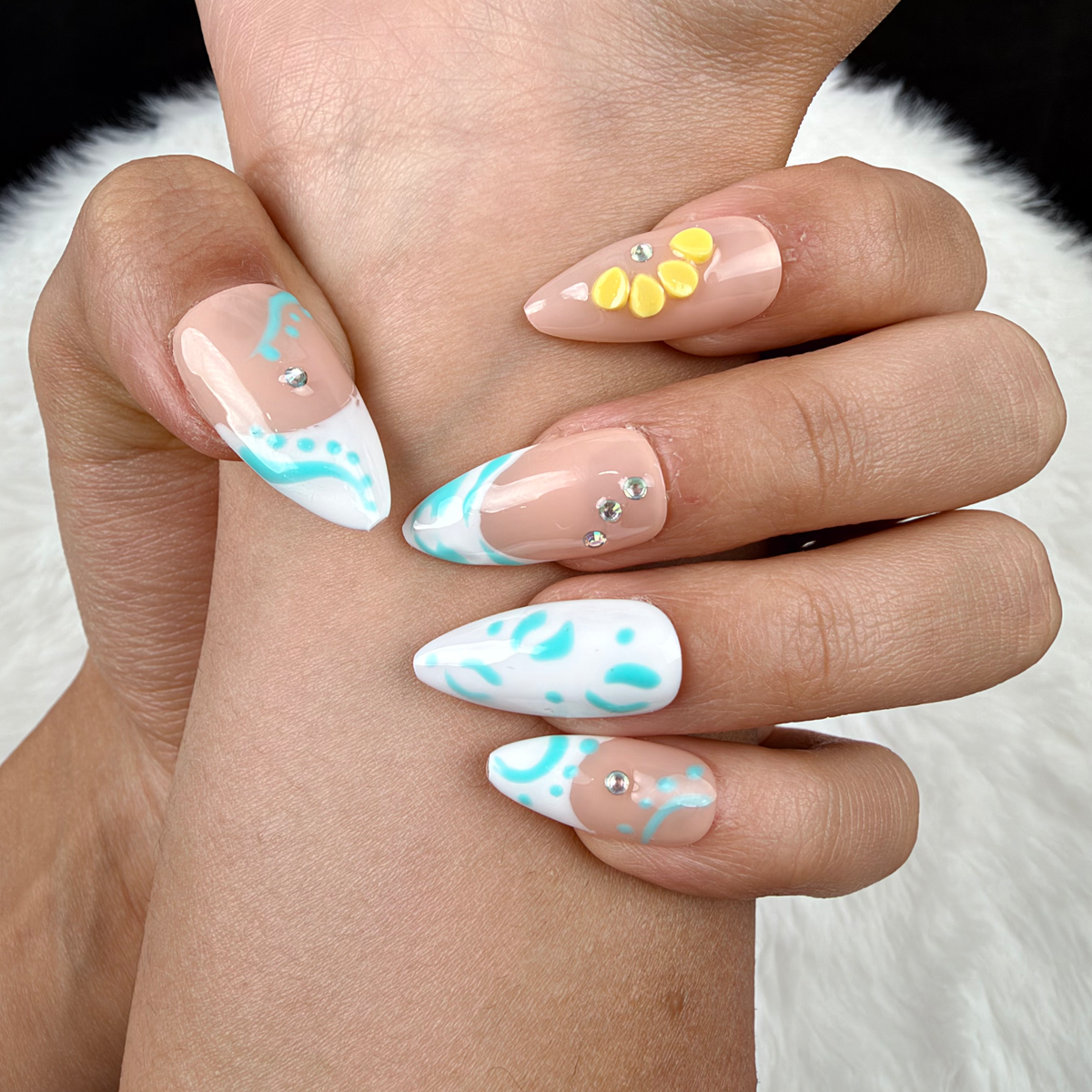 Detail shot of Turquoise Tide turquoise French tip and yellow floral almond press-on nails on hand