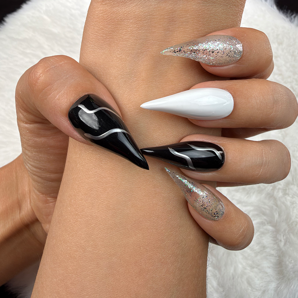 Close-up of hands wearing Silver Current black, white and silver glitter stiletto press-on nails