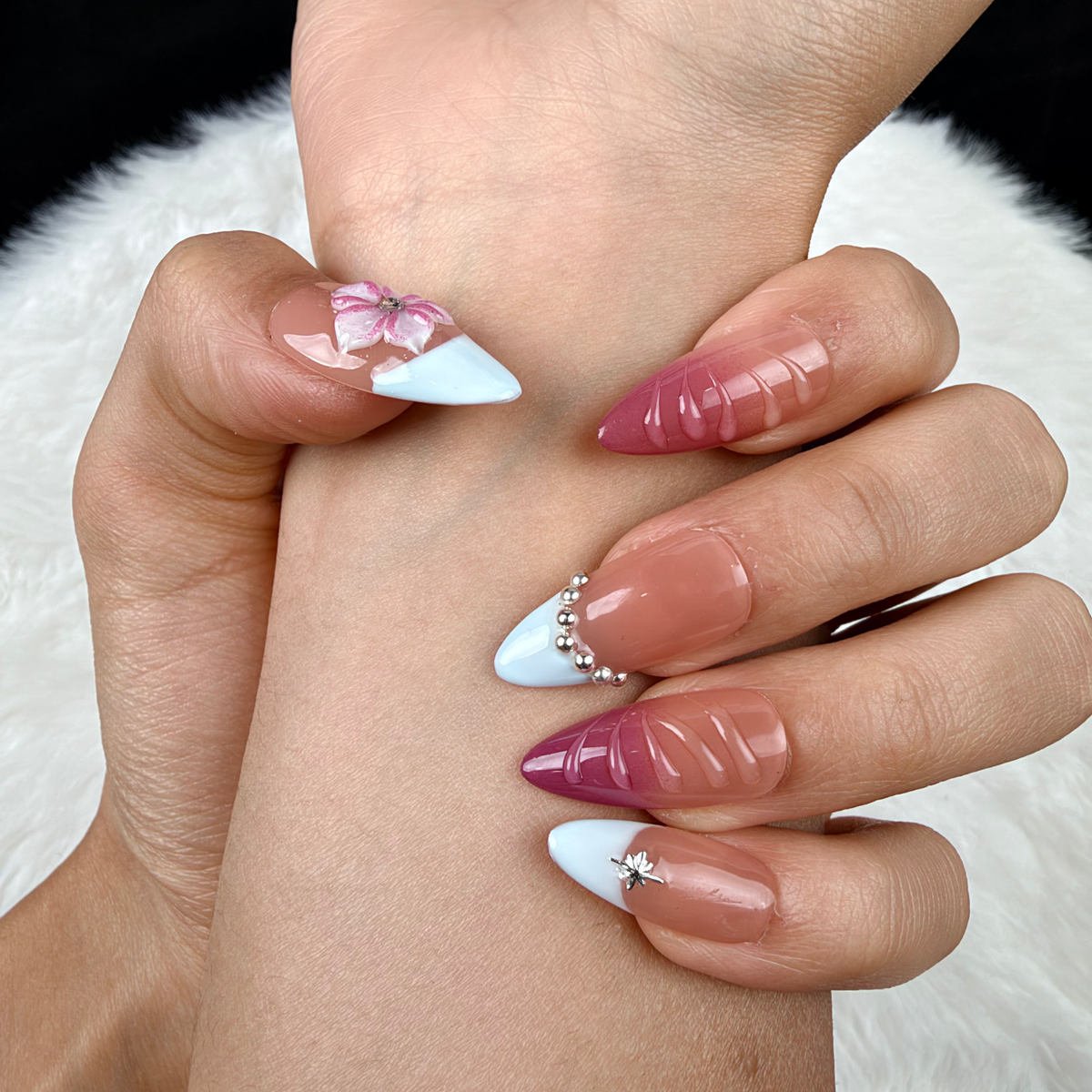 Detail shot of Rose Lattice pink French tip almond press-on nails with raised flowers on hand