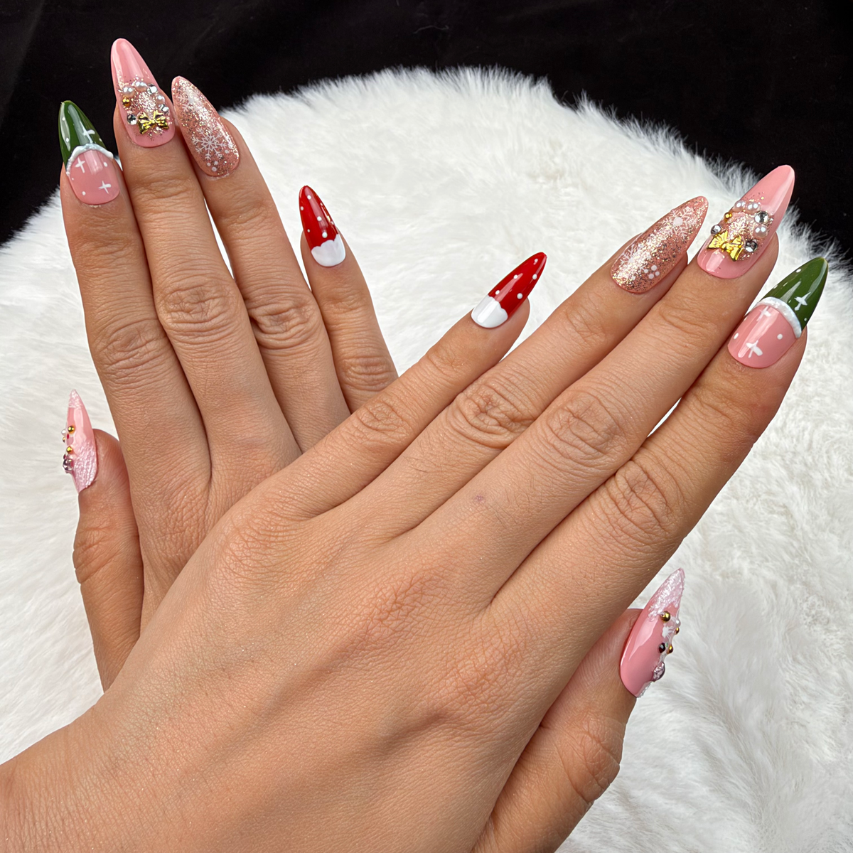 Detail shot of Pink Noel pink, red and green Christmas almond press-on nails on hand