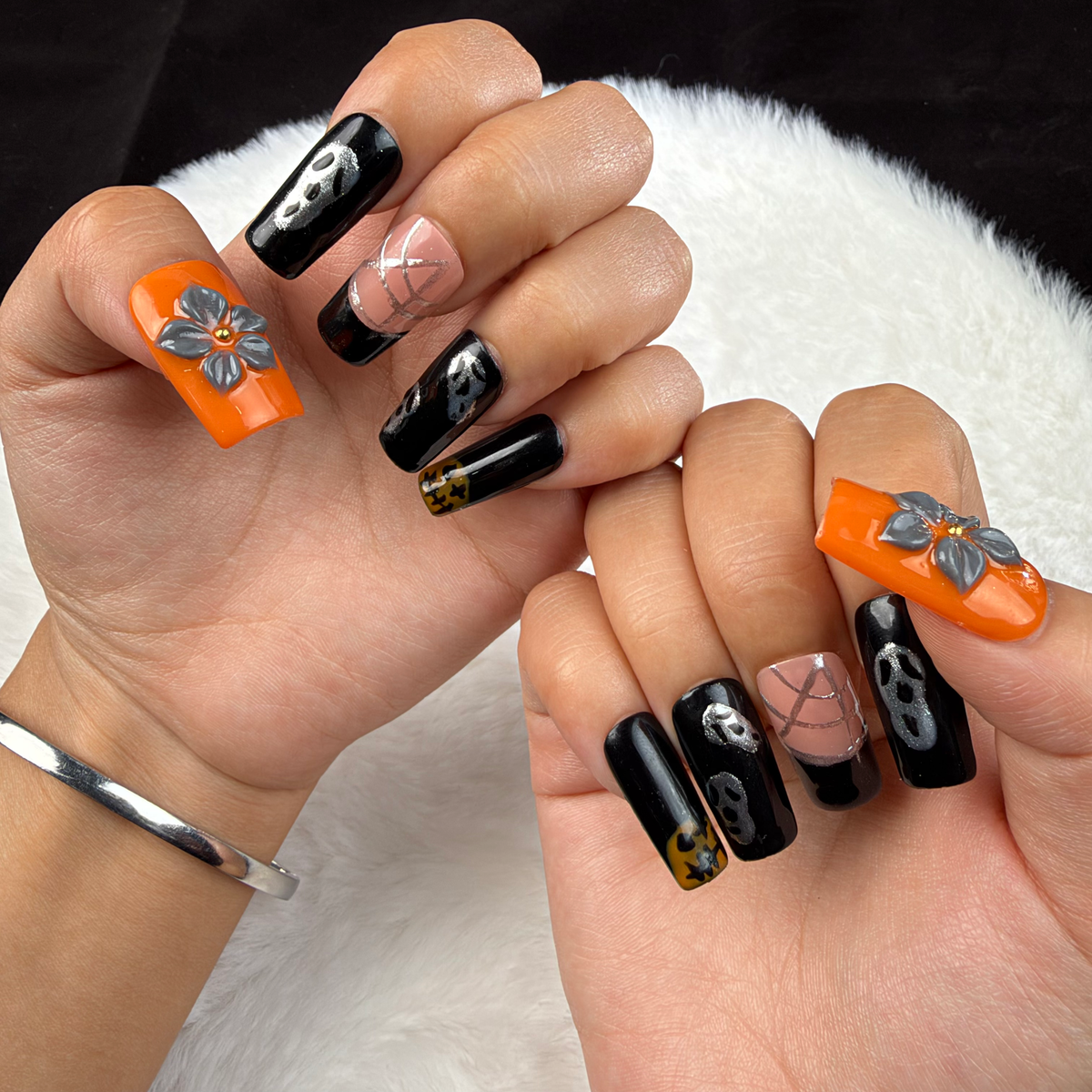 Hands wearing Midnight Harvest orange and black skull Halloween square press-on nails