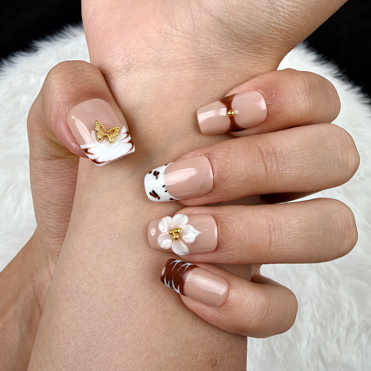 Detail shot of Caramel Bouquet brown, white and nude floral square press-on nails on hand