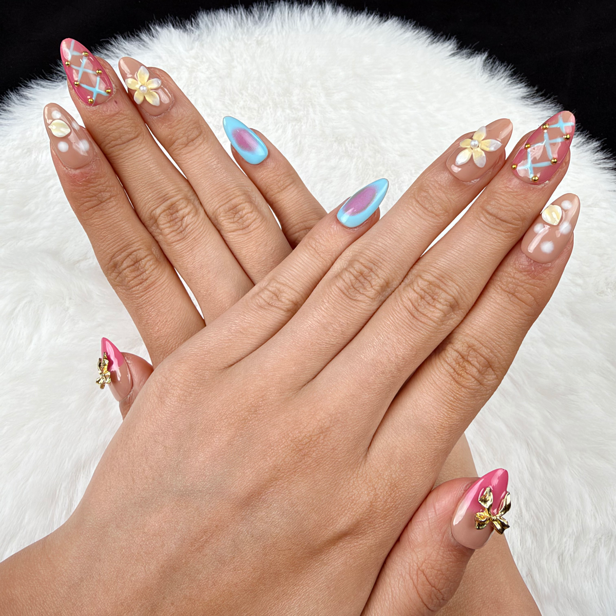 Hands wearing Sorbet Charms pink, blue and peach floral almond press-on nails with gold charms