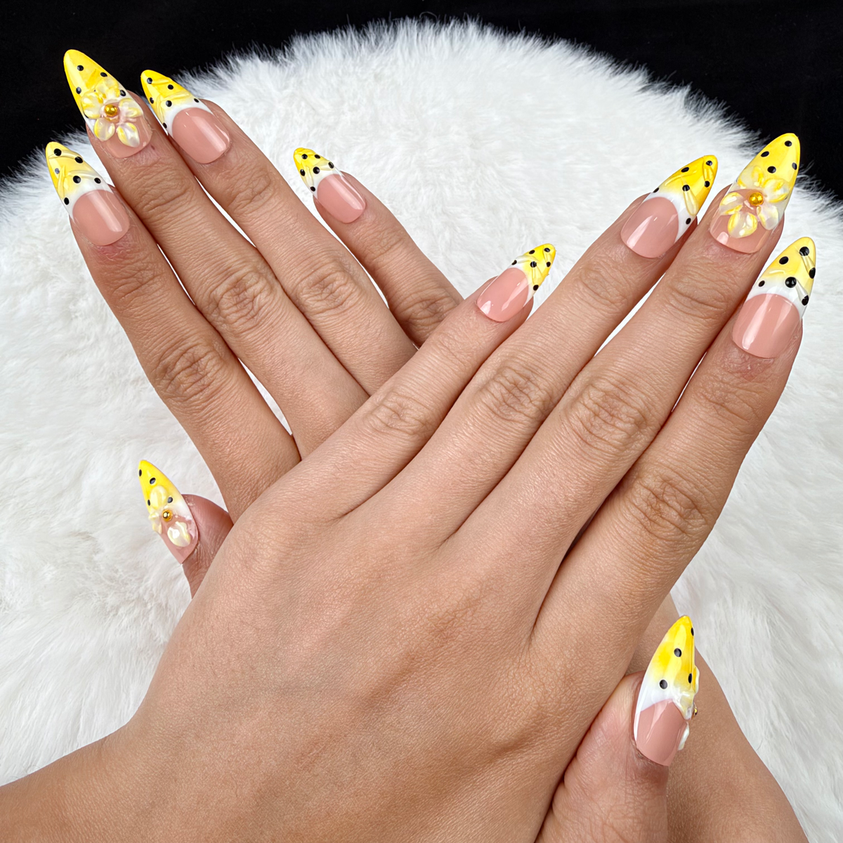 Hands wearing Sunny Petal yellow polka dot French tip floral almond press-on nails