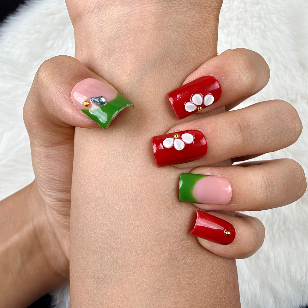 Detail shot of Garden Contrast red, green and white floral square press-on nails on hand