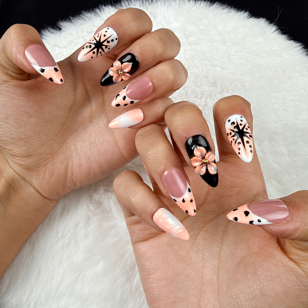 Close-up of hands wearing Peach Graphic Bloom peach and black floral almond press-on nails