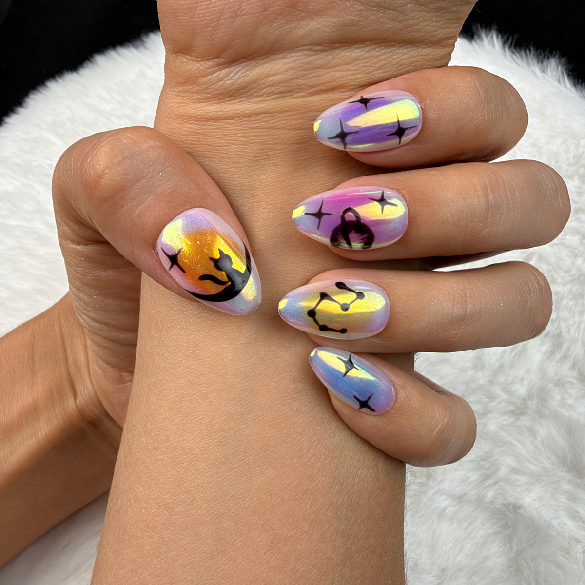 Detail shot of Aurora Signs iridescent celestial almond press-on nails on hand