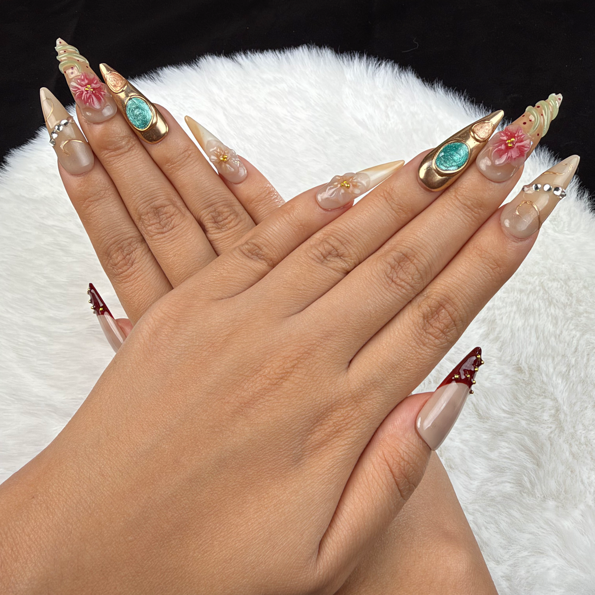 Detail shot of Gilded Garden nude, burgundy and turquoise floral almond press-on nails with gold accents on hand