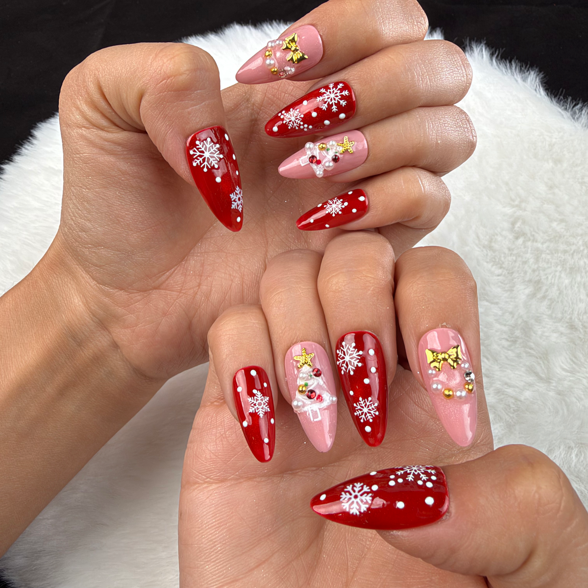 Hands wearing Scarlet Snowfall red and pink snowflake Christmas almond press-on nails