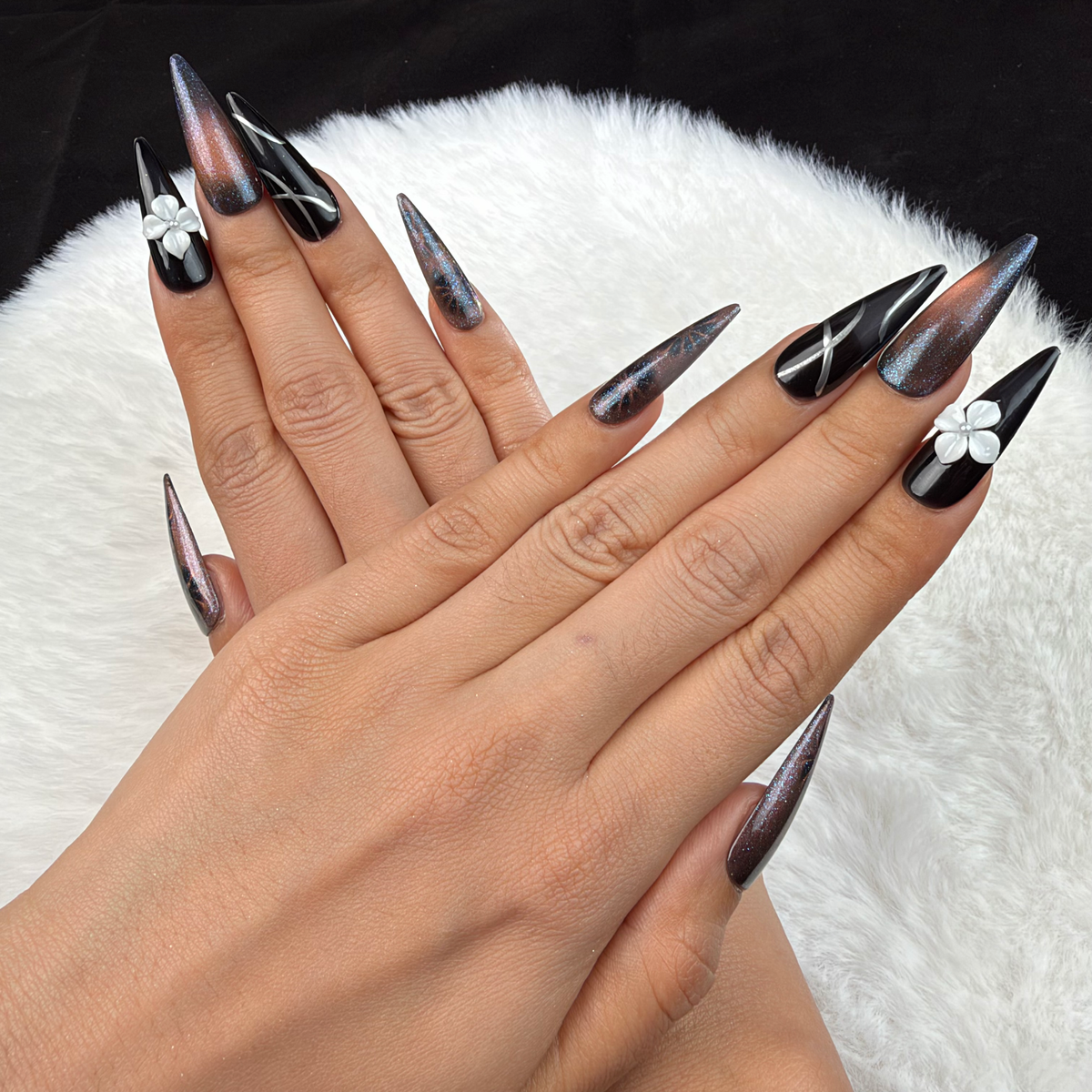 Detail shot of Smoky Bloom black and smoky grey stiletto press-on nails with a white 3D flower on hand