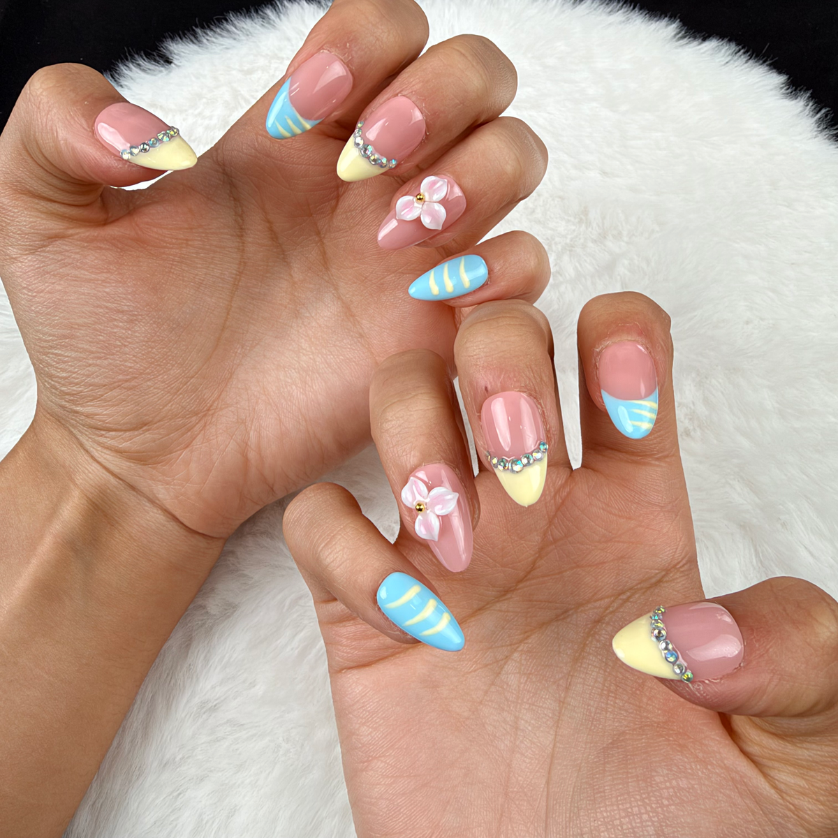 Close-up of hands wearing Lemon Sky yellow and blue French tip floral almond press-on nails