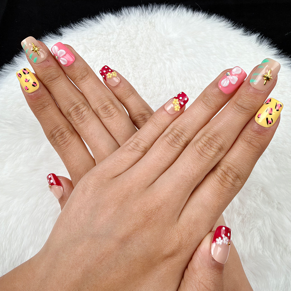 Hands wearing Garden Party red, yellow and pink floral square press-on nails