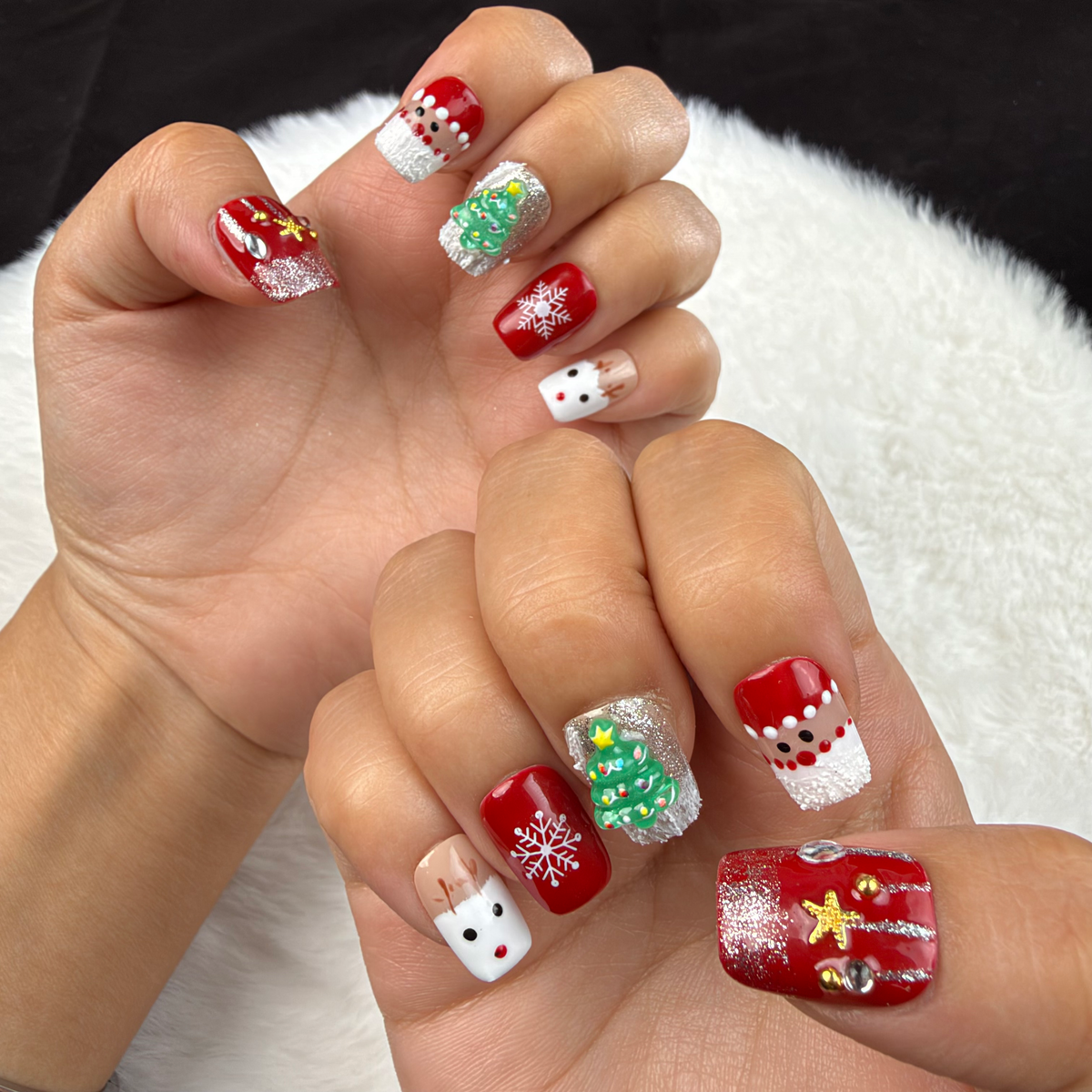 Hands wearing Christmas Patchwork red and green Christmas square press-on nails with trees and snowflakes