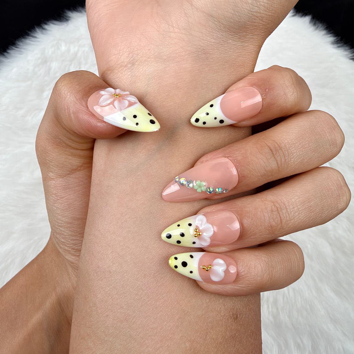 Detail shot of Lemon Blossom yellow polka dot French tip floral almond press-on nails on hand