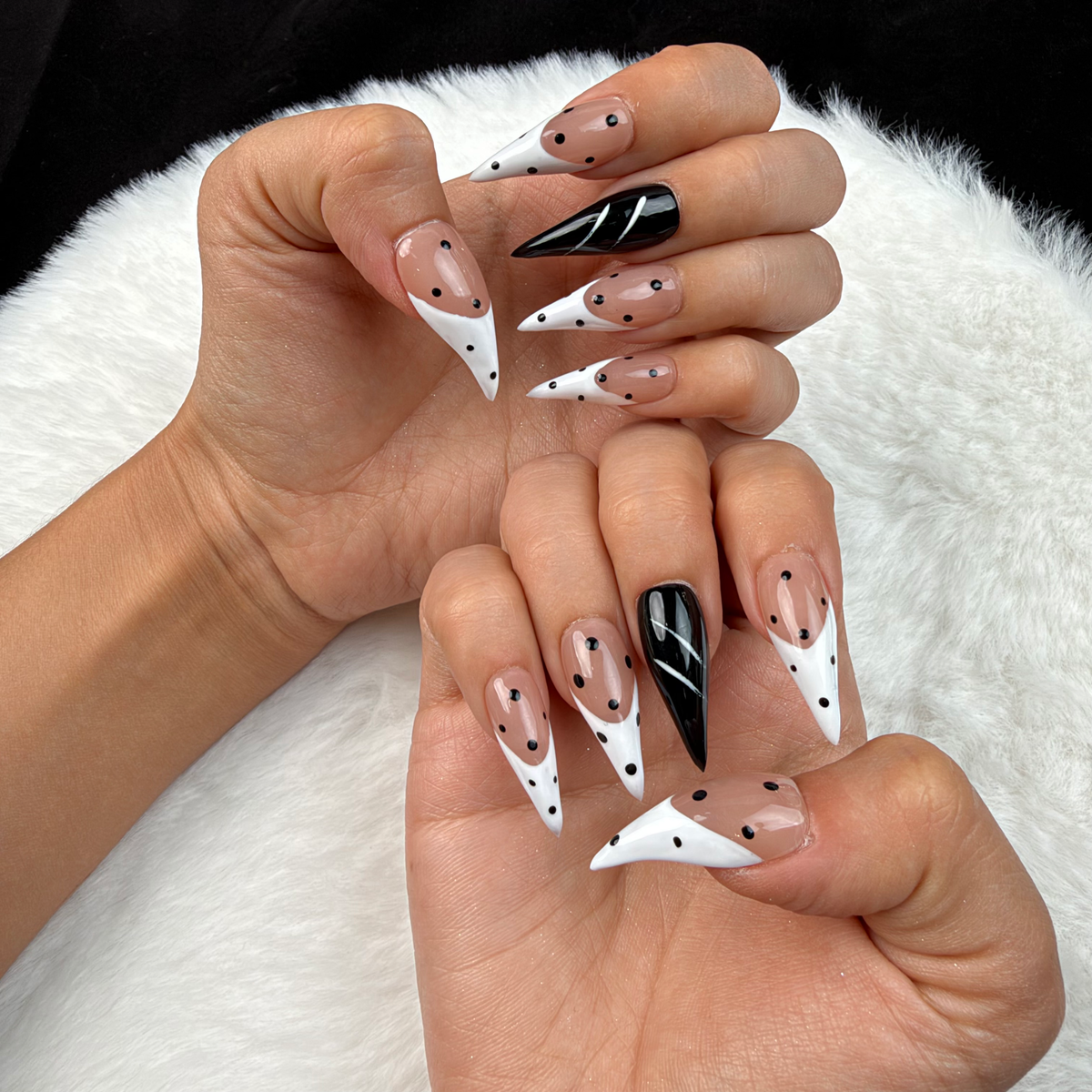 Hands wearing Ink Dots black and white polka dot stiletto press-on nails