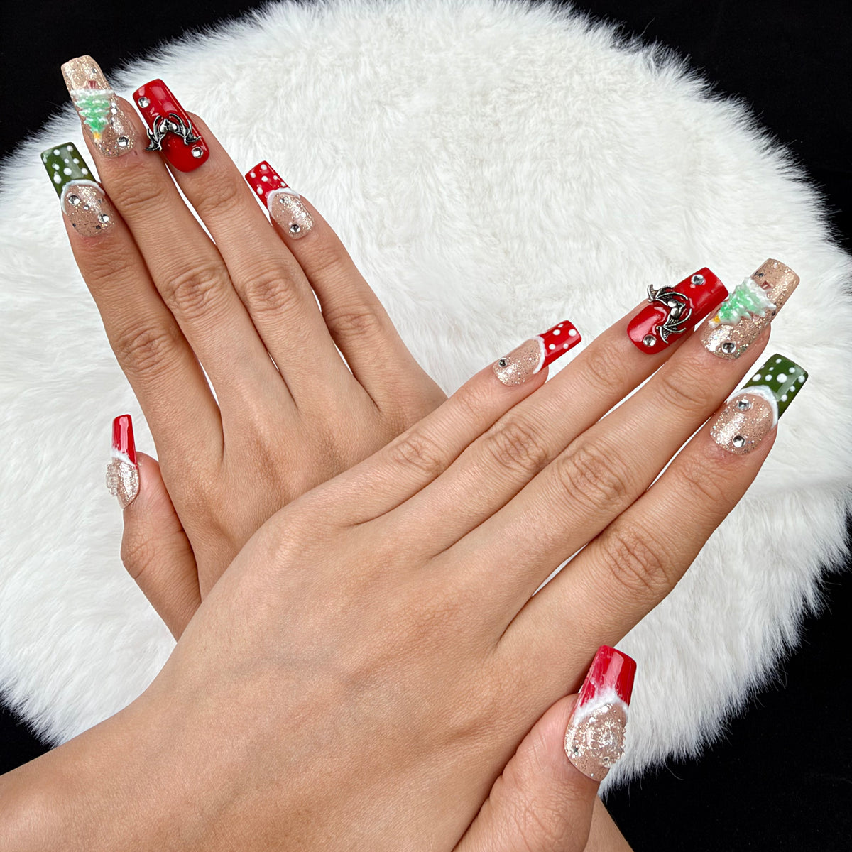 Hands wearing Gingerbread Party red, green and glitter Christmas square press-on nails with gingerbread and tree designs