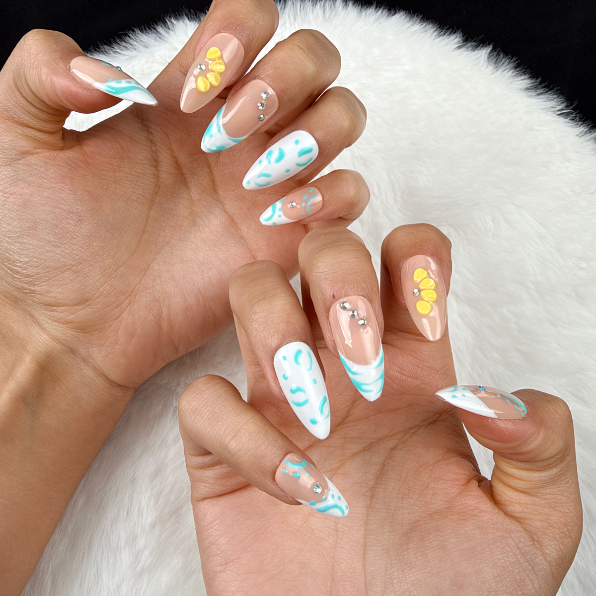 Close-up of hands wearing Turquoise Tide turquoise French tip and yellow floral almond press-on nails