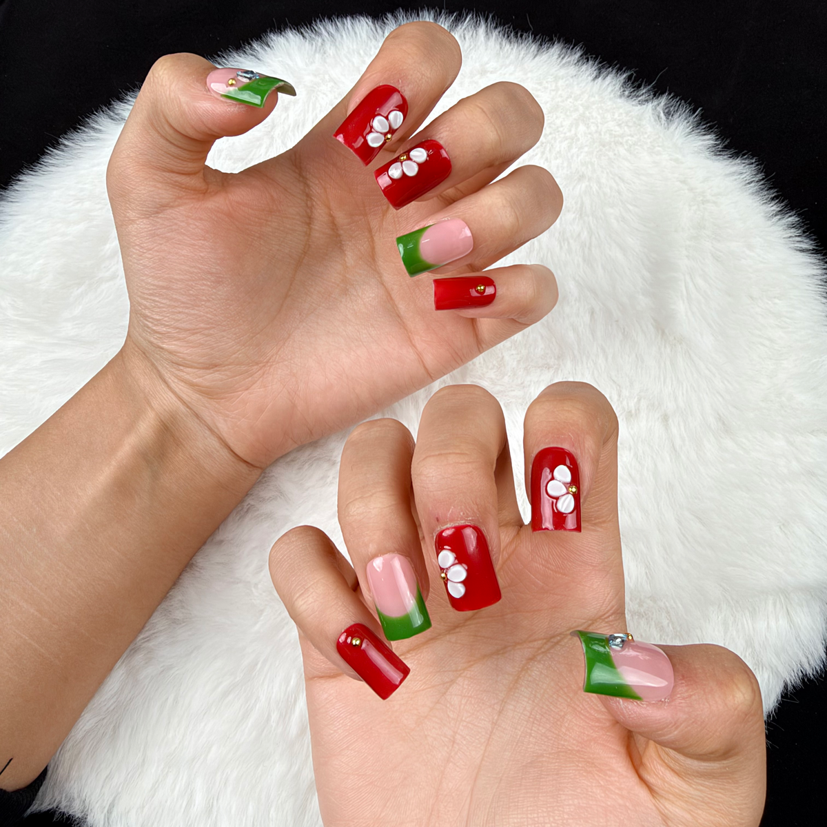 Close-up of hands wearing Garden Contrast red, green and white floral square press-on nails