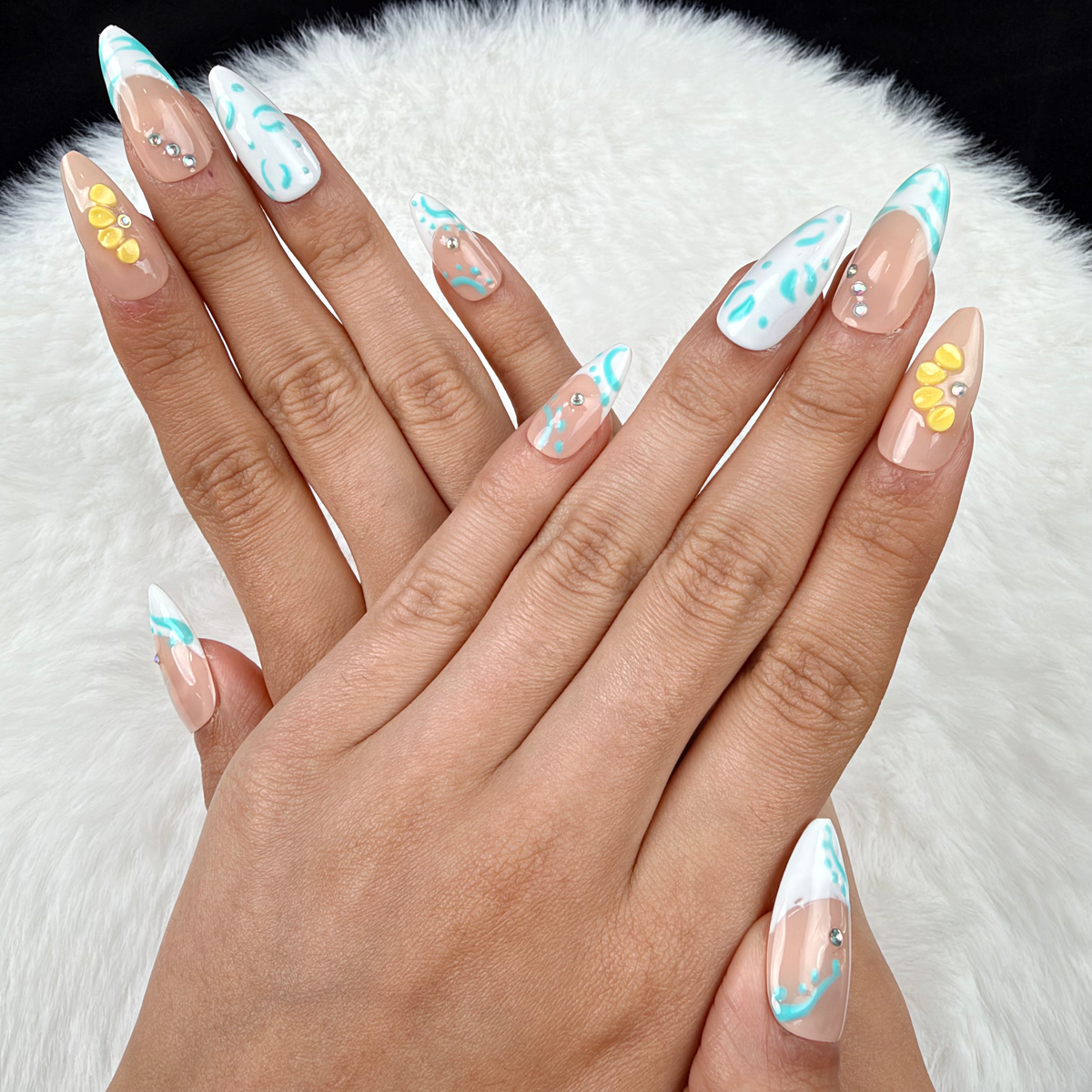 Hands wearing Turquoise Tide turquoise French tip and yellow floral almond press-on nails