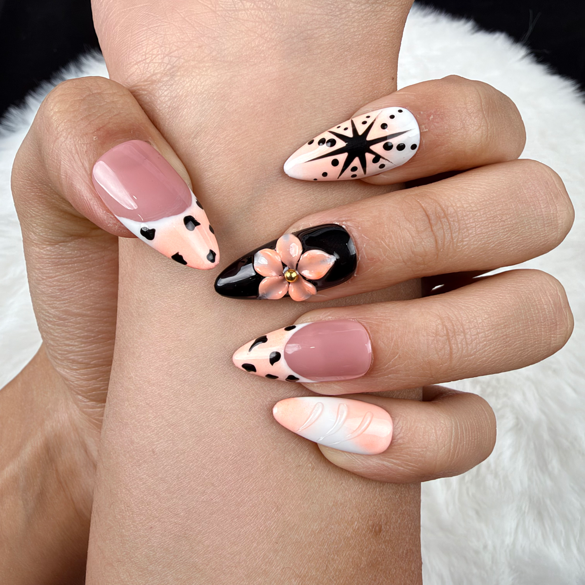 Detail shot of Peach Graphic Bloom peach and black floral almond press-on nails on hand