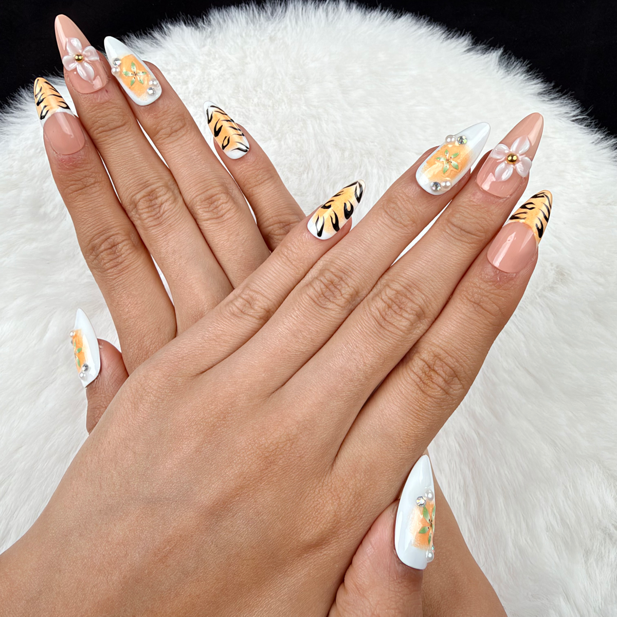 Hands wearing Tiger Lily orange tiger stripe and floral almond press-on nails