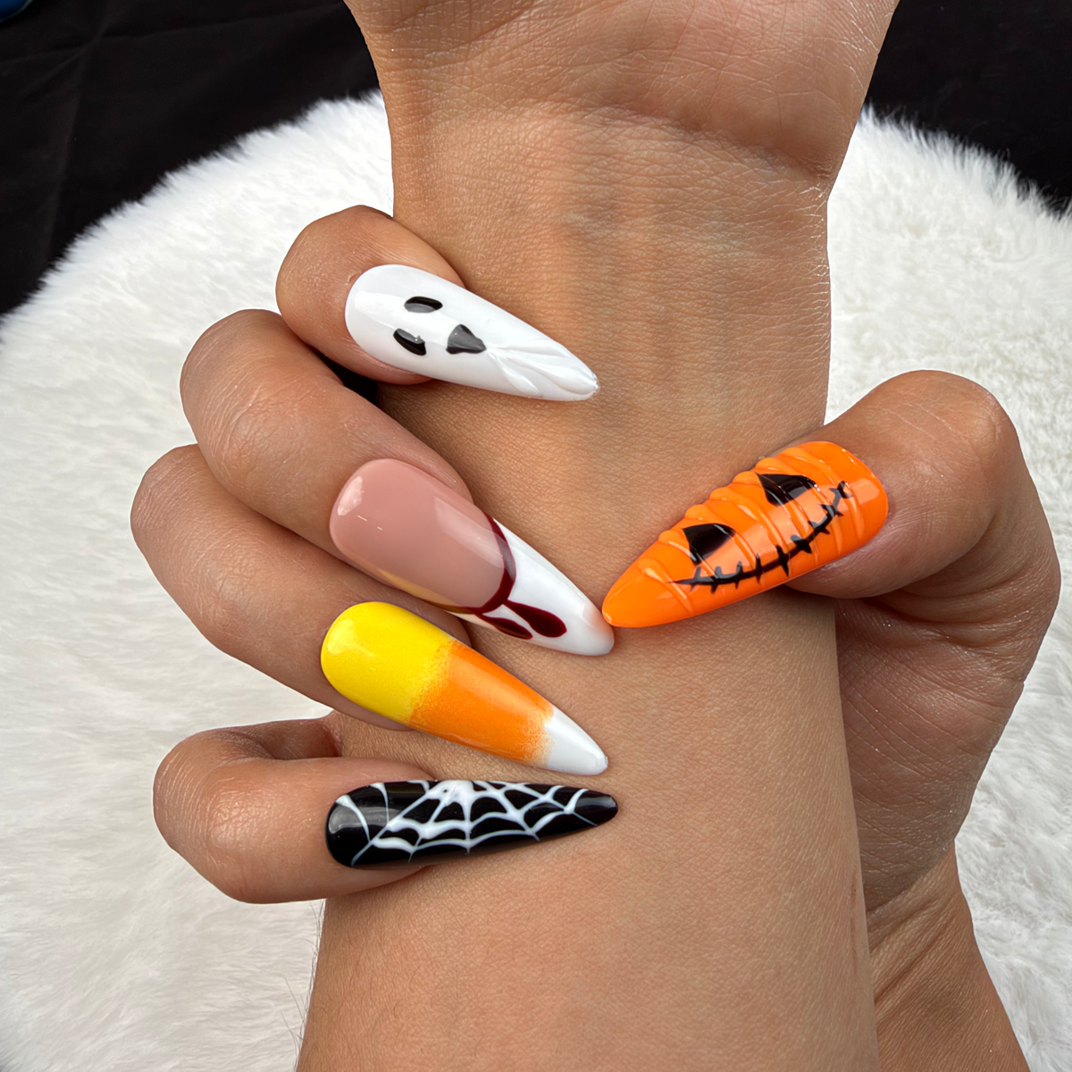 Detail shot of Haunted Parade ghost, pumpkin and spiderweb Halloween stiletto press-on nails on hand
