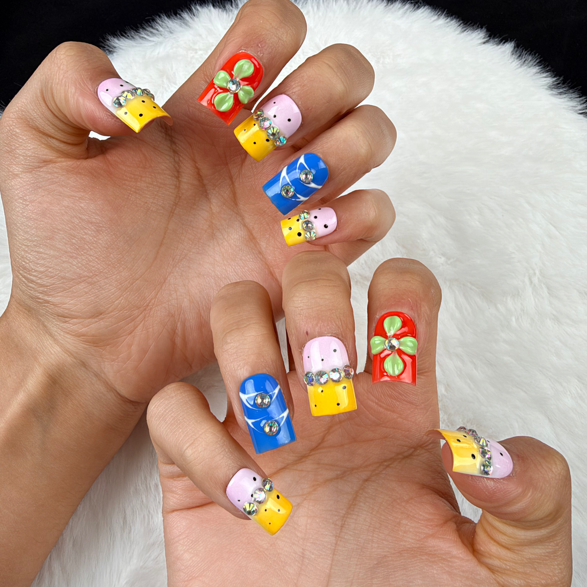 Close-up of hands wearing Colour Parade yellow, pink and blue floral square press-on nails