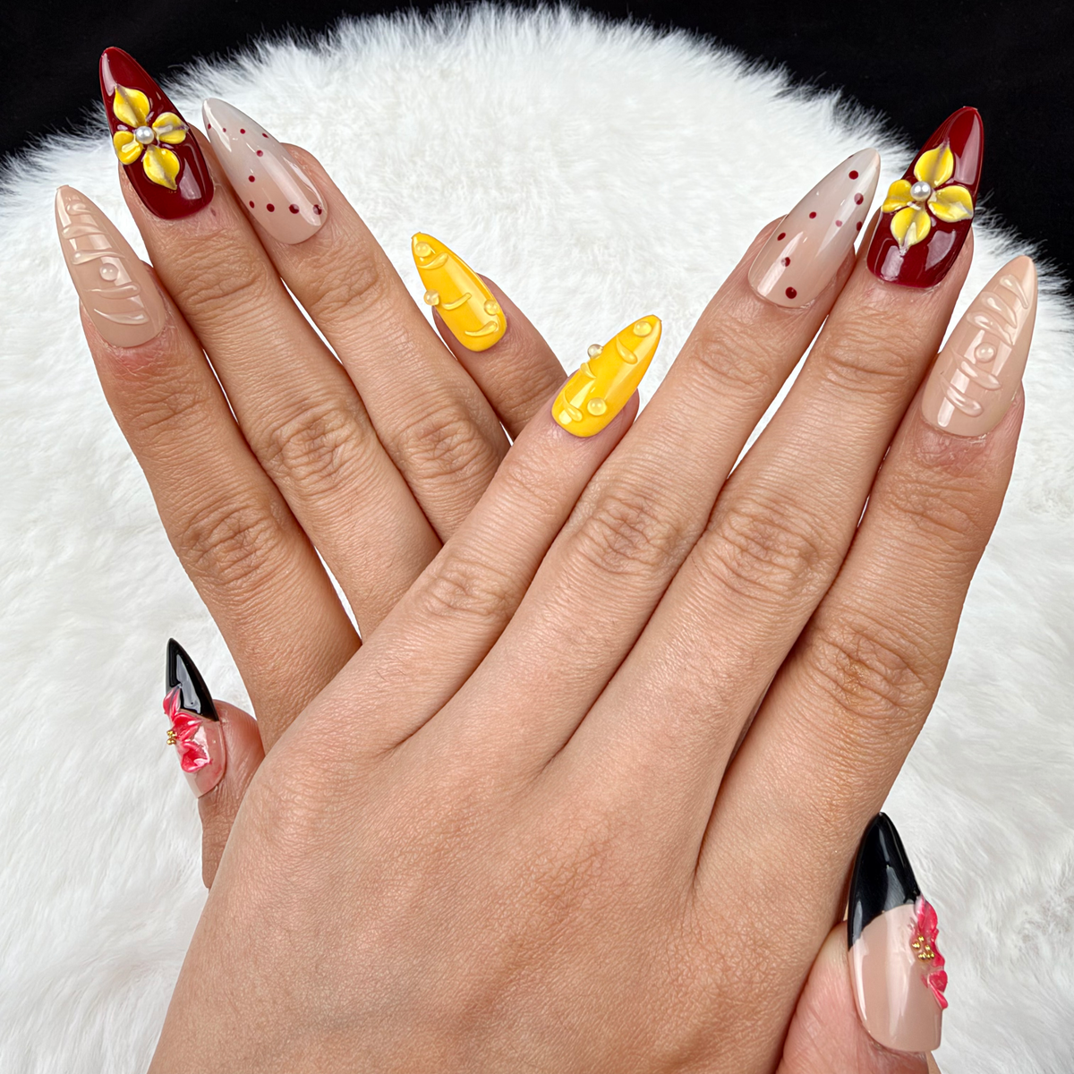 Hands wearing Golden Orchid yellow, burgundy and black floral almond press-on nails