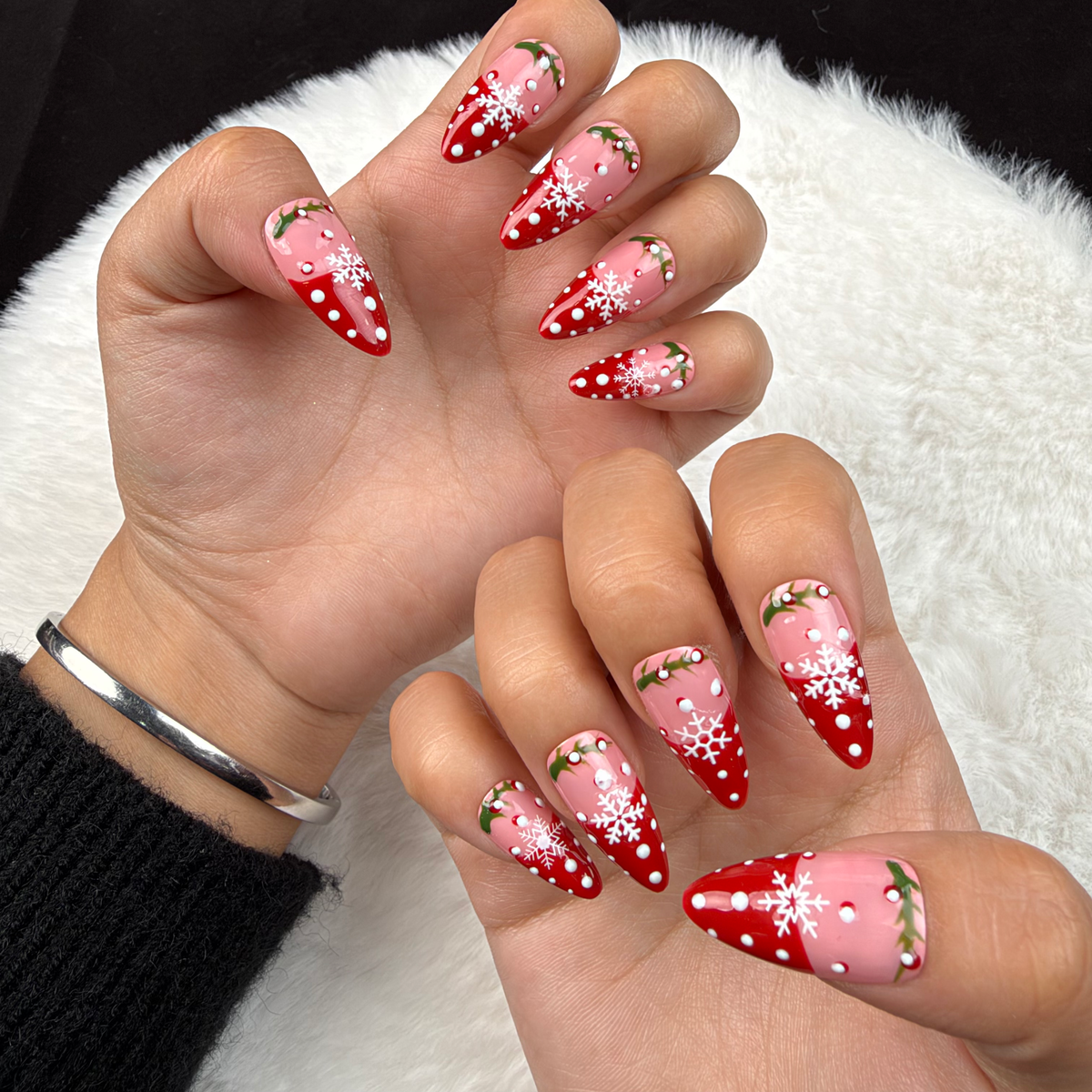 Hands wearing Holly Snow red and pink snowflake French tip Christmas almond press-on nails