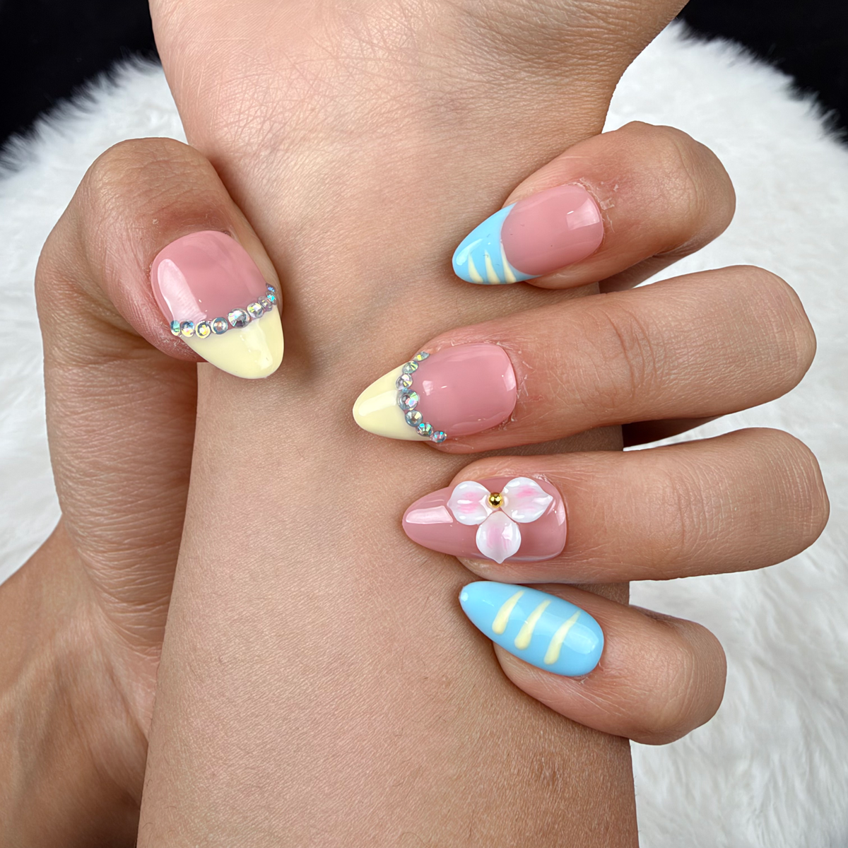 Detail shot of Lemon Sky yellow and blue French tip floral almond press-on nails on hand