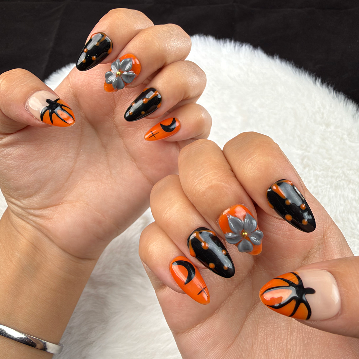 Hands wearing Haunted Bloom orange and black Halloween floral almond press-on nails