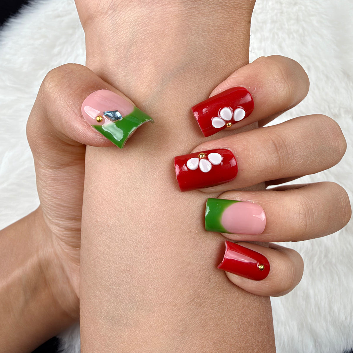 Close-up of hands wearing Garden Contrast red, green and white floral square press-on nails