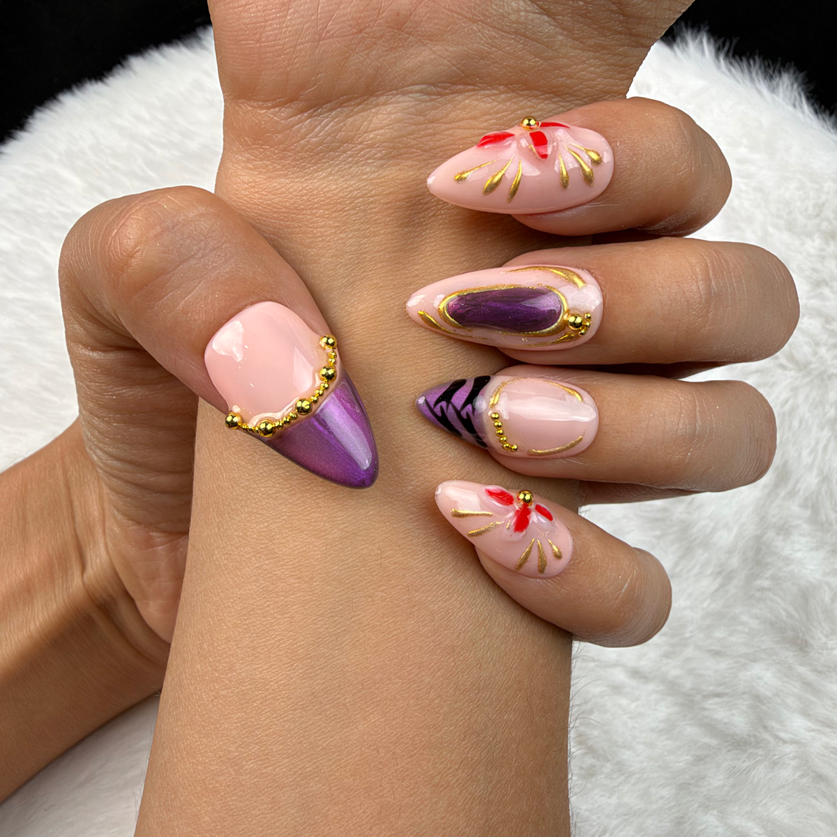 Close-up of hands wearing Amethyst Bloom purple and gold floral almond press-on nails