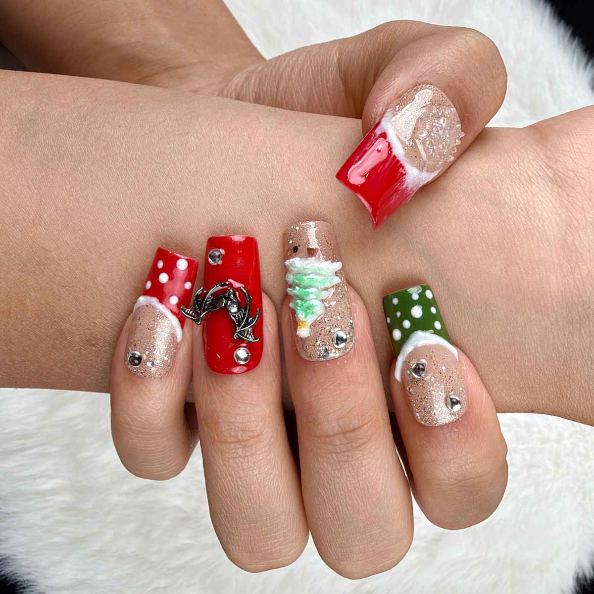 Hands wearing Gingerbread Party red, green and glitter Christmas square press-on nails with gingerbread and tree designs