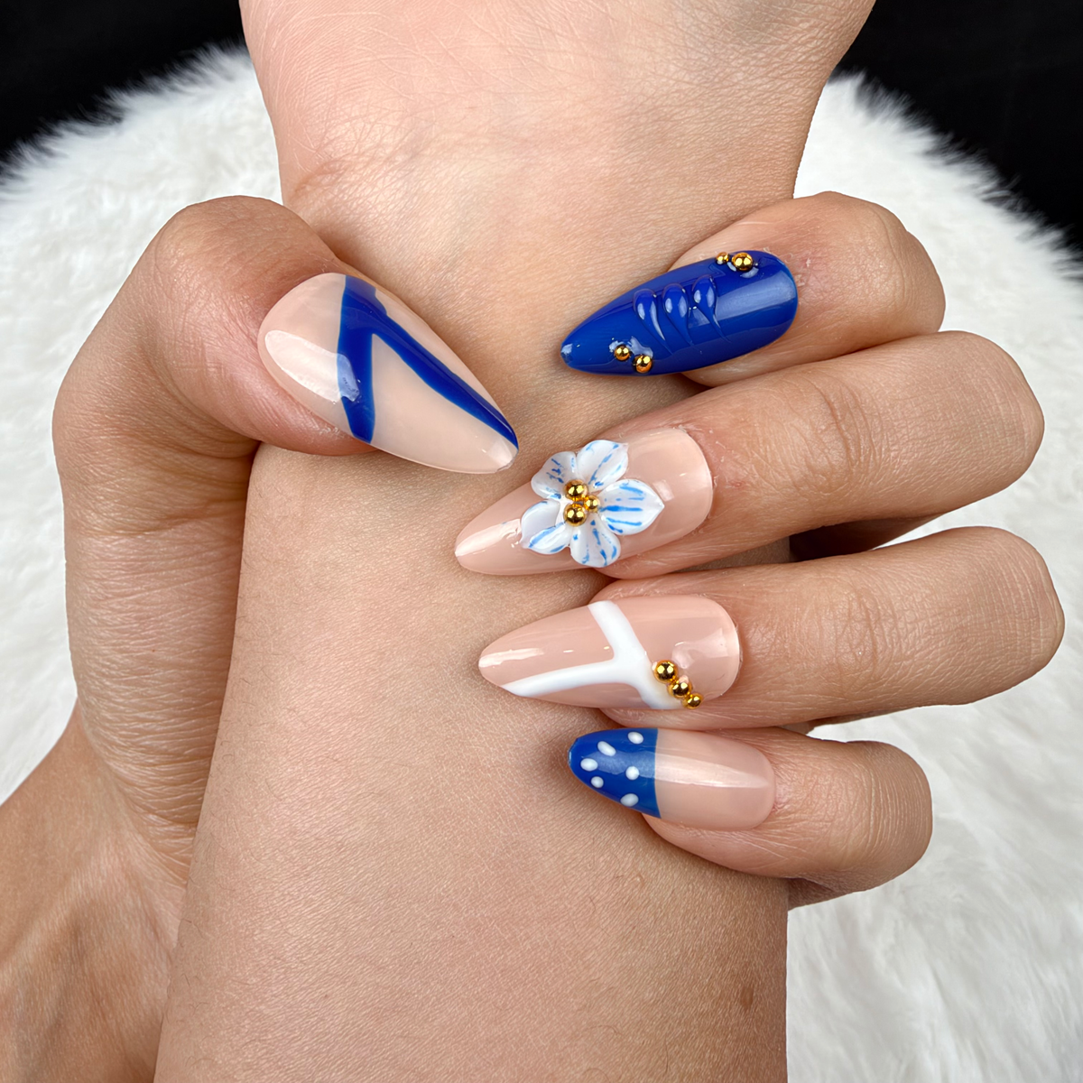 Detail shot of Cobalt Petal cobalt blue and nude floral almond press-on nails on hand