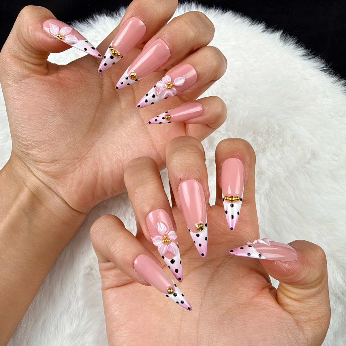 Close-up of hands wearing Blush Polka pink polka dot French tip floral almond press-on nails