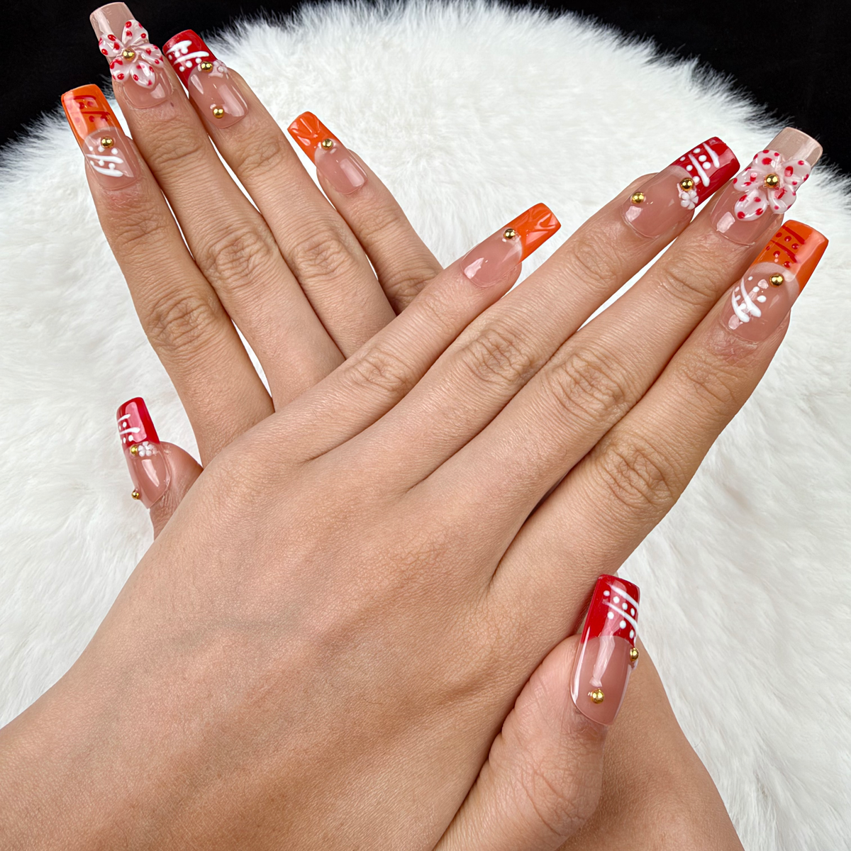 Hands wearing Coral Ribbon coral and orange floral square press-on nails