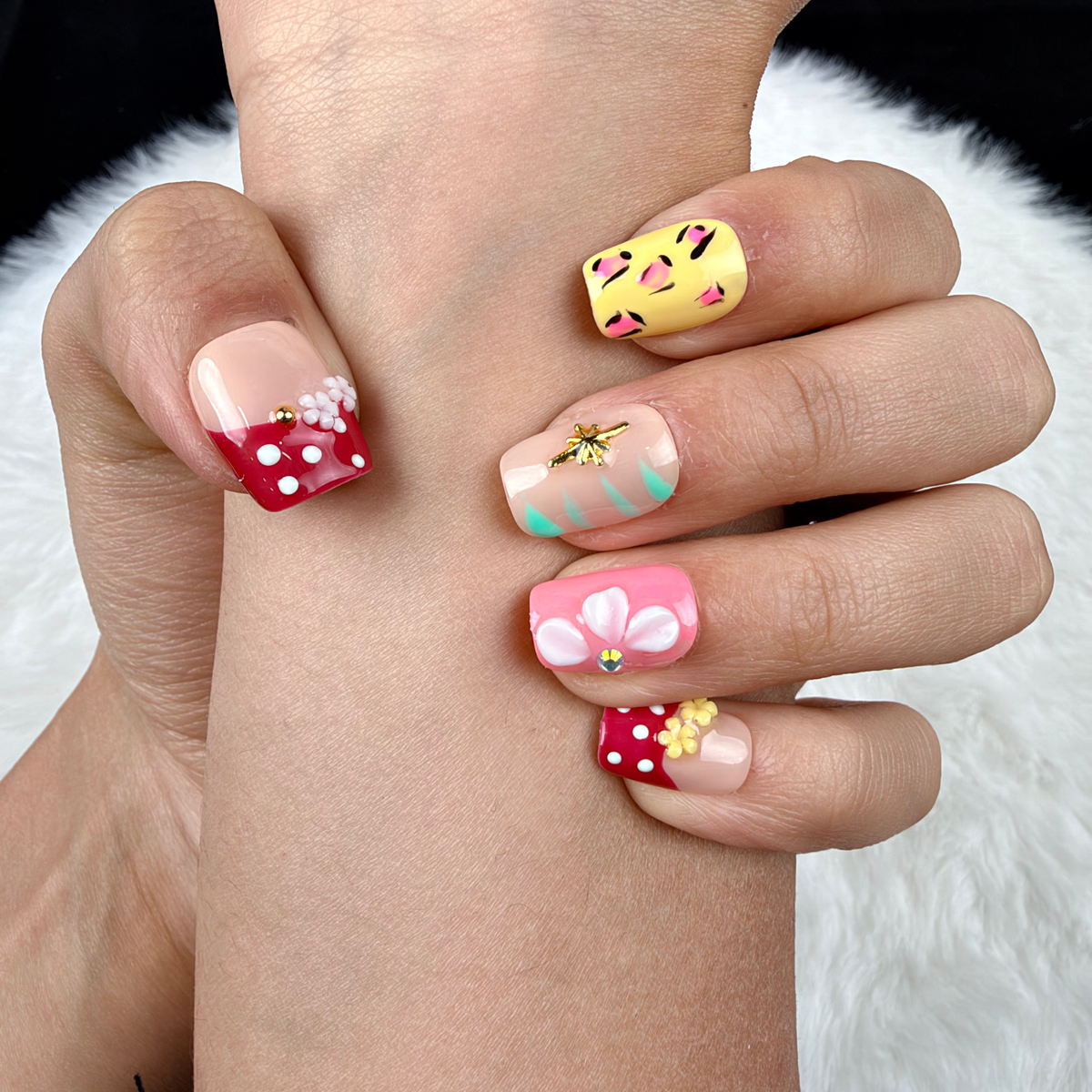 Detail shot of Garden Party red, yellow and pink floral square press-on nails on hand