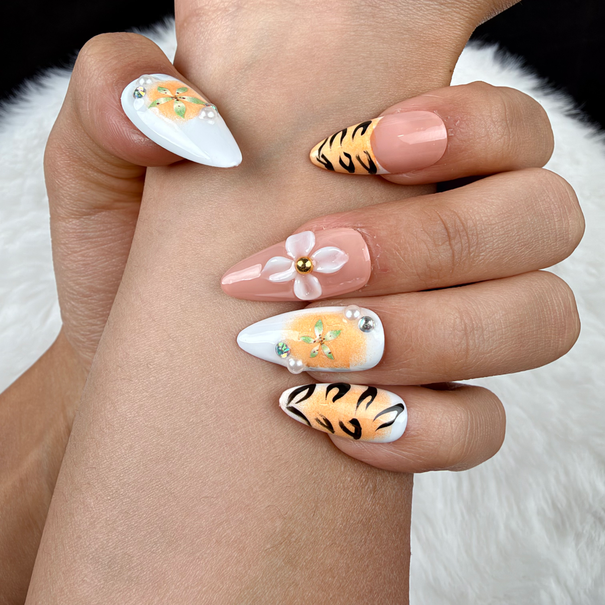 Detail shot of Tiger Lily orange tiger stripe and floral almond press-on nails on hand