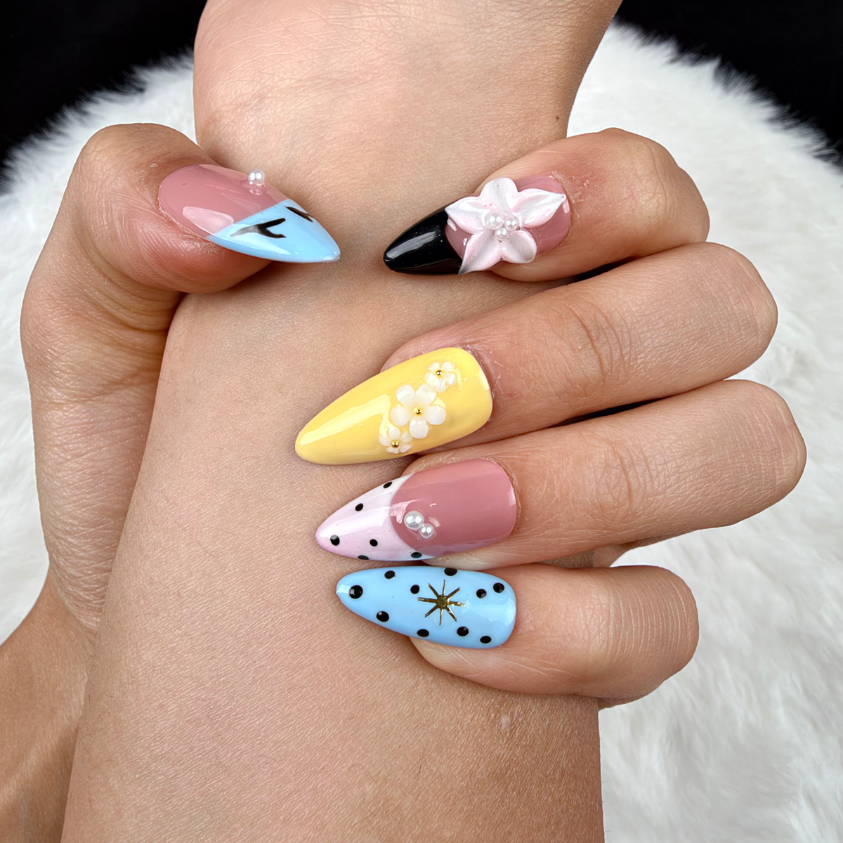Detail shot of Pastel Graphic Garden blue, yellow and pink floral almond press-on nails on hand