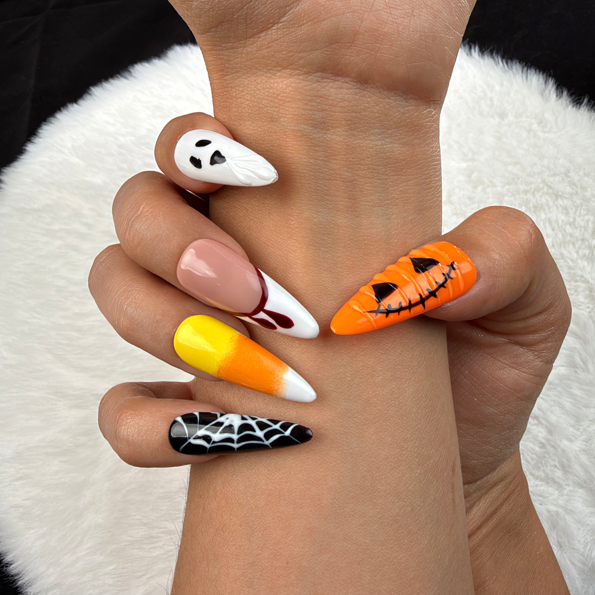 Close-up of hands wearing Haunted Parade ghost, pumpkin and spiderweb Halloween stiletto press-on nails