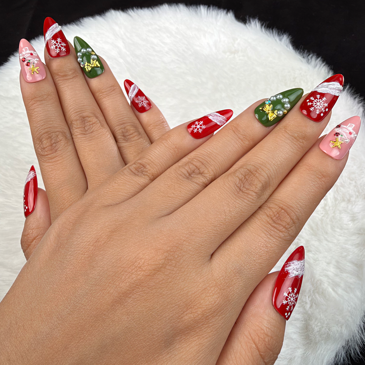 Detail shot of Evergreen Ribbon red, pink and green snowflake Christmas almond press-on nails on hand