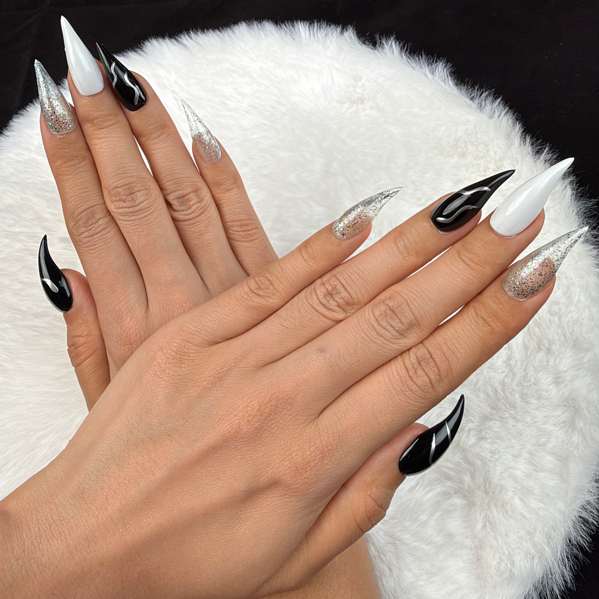 Detail shot of Silver Current black, white and silver glitter stiletto press-on nails on hand
