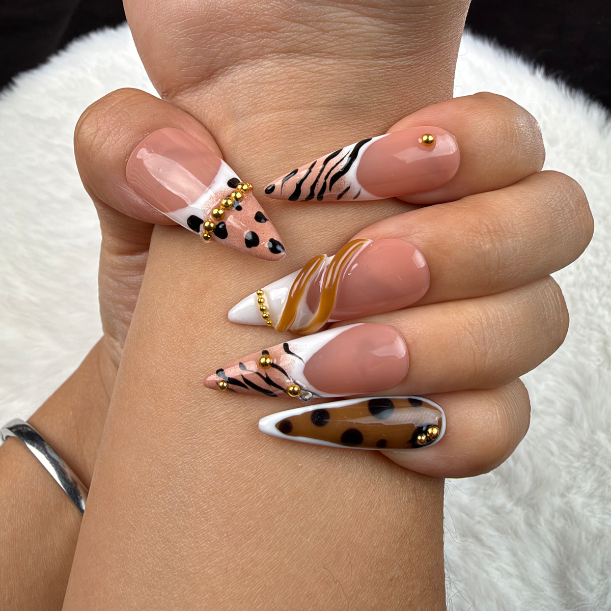 Hands wearing Wild French animal print French tip almond press-on nails with gold accents