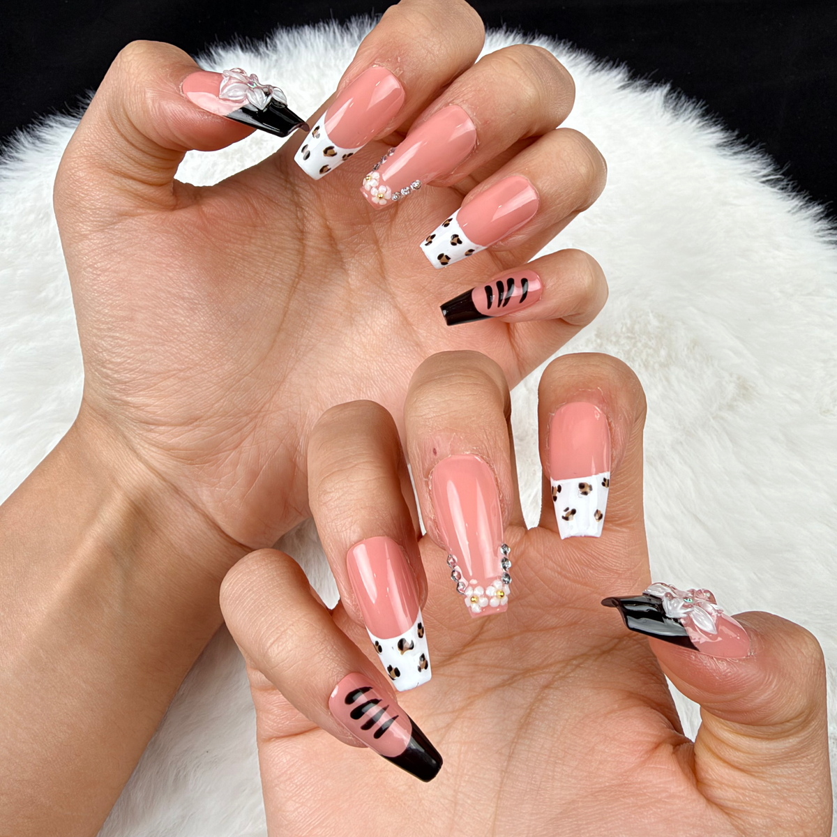 Close-up of hands wearing Noir Bouquet black French tip and pale pink floral square press-on nails
