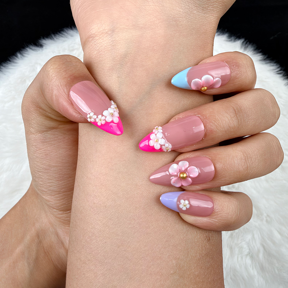 Detail shot of Floral Canopy pink, blue and lilac French tip floral almond press-on nails on hand