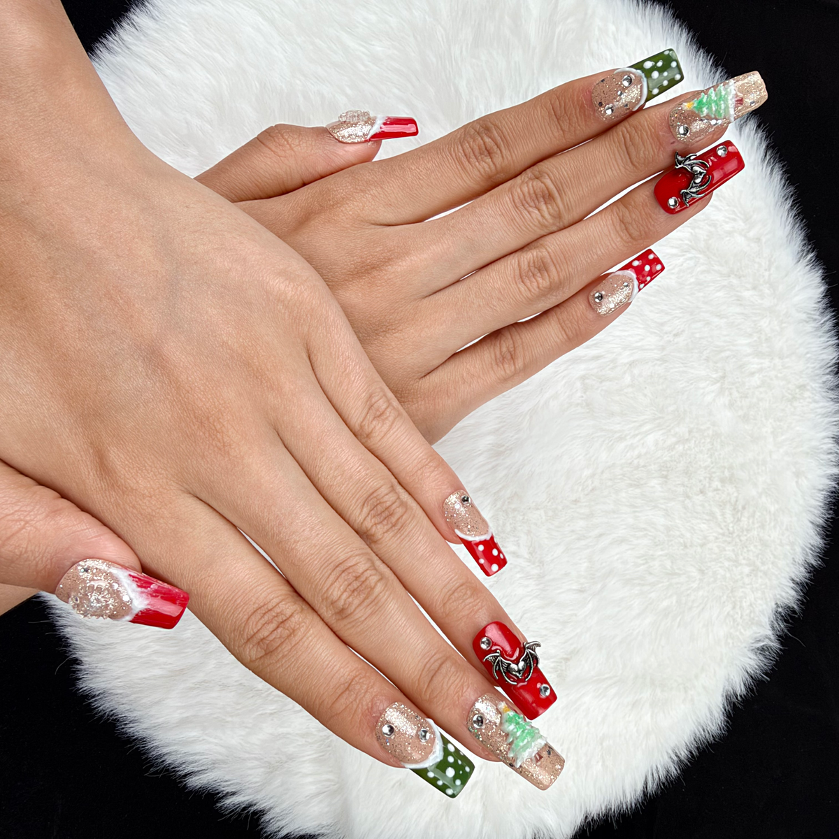 Hands wearing Gingerbread Party red, green and glitter Christmas square press-on nails with gingerbread and tree designs